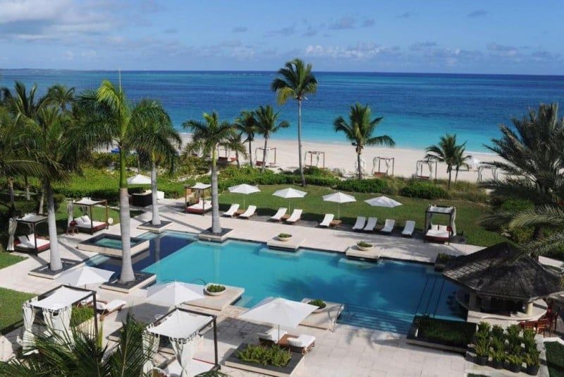 Grace Bay Club exterior with beachfront infinity pools and sun loungers overlooking the crystal-clear waters of Grace Bay Beach